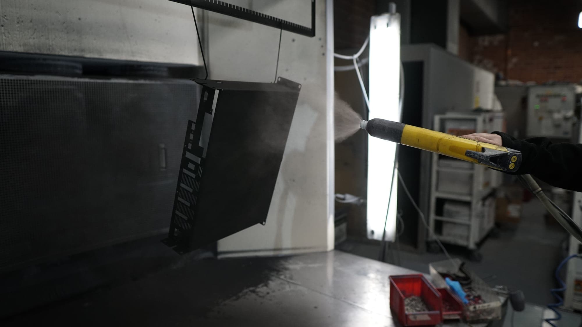 Powder coating an enclosure, side view: the powder cloud from the gun onto the surface