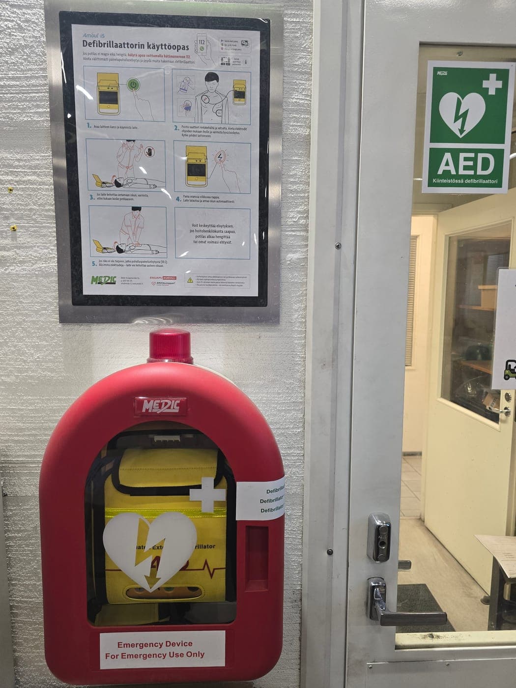 Defibrillator cabinet and AED instructions next to a door in our premises